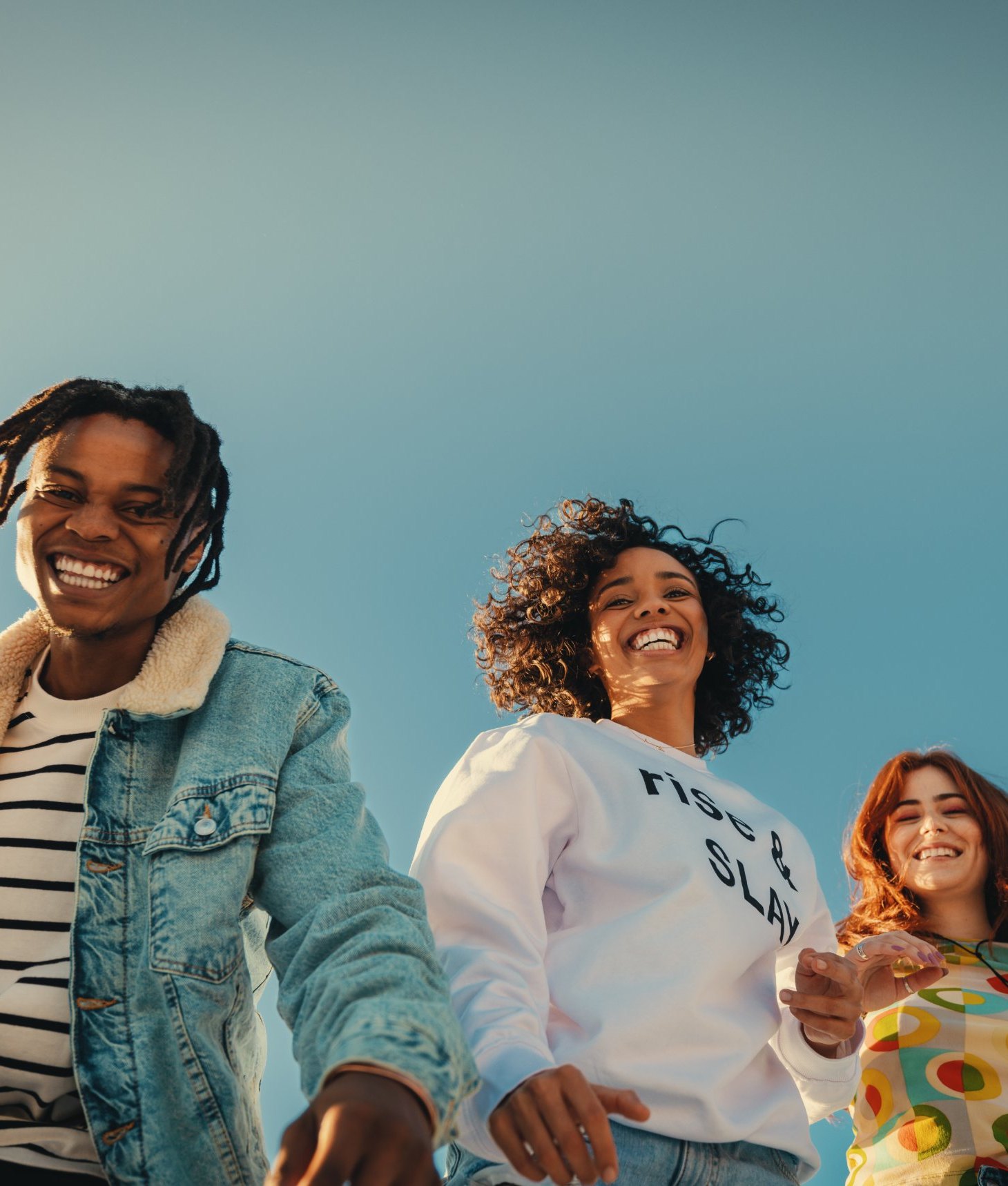 Four friends laughing under a clear blue sky