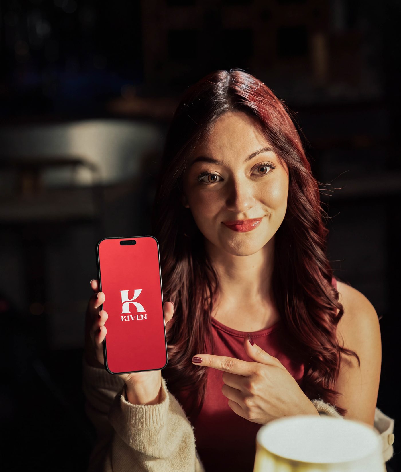 A woman holding up her phone with the Kiven splash screen