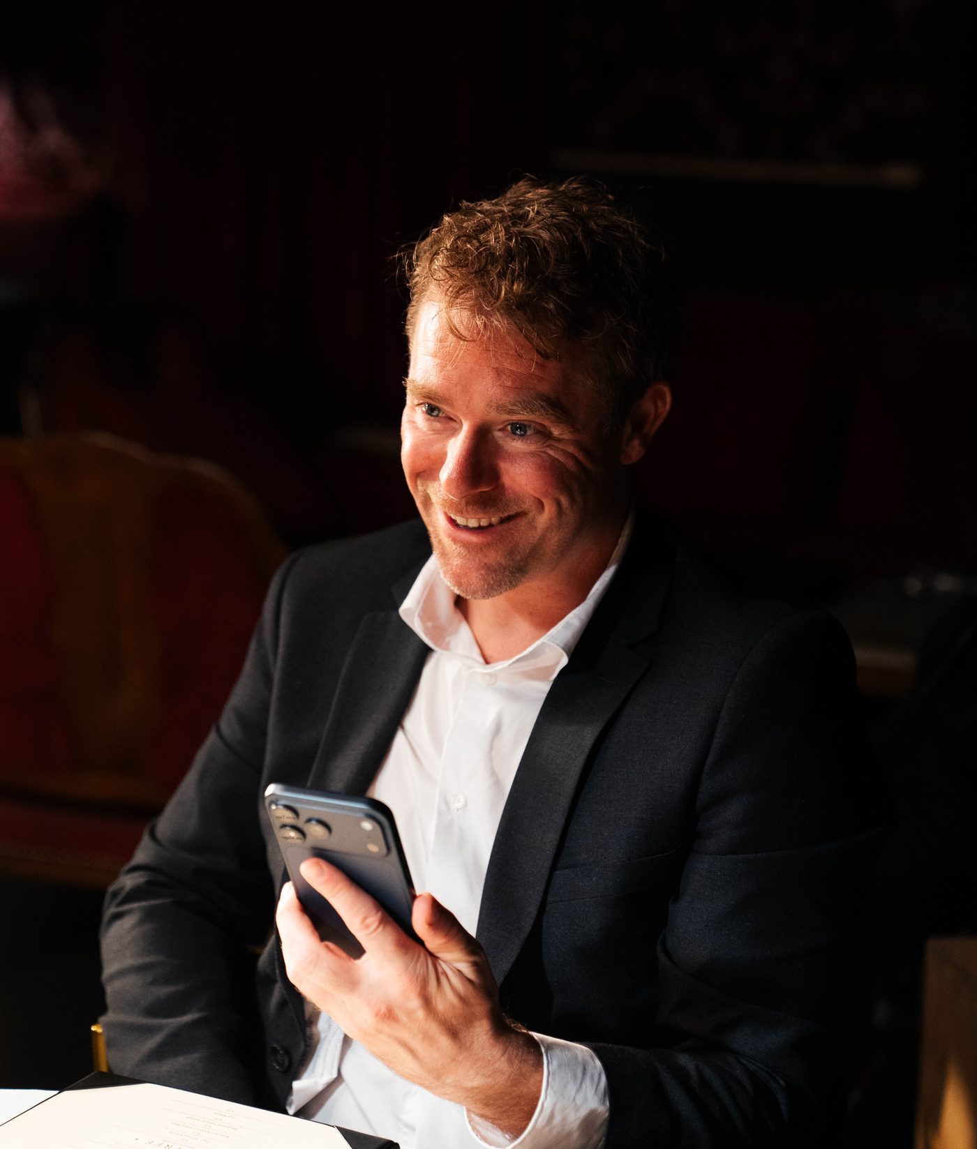 A man in a suit checking the Kiven app at dinner