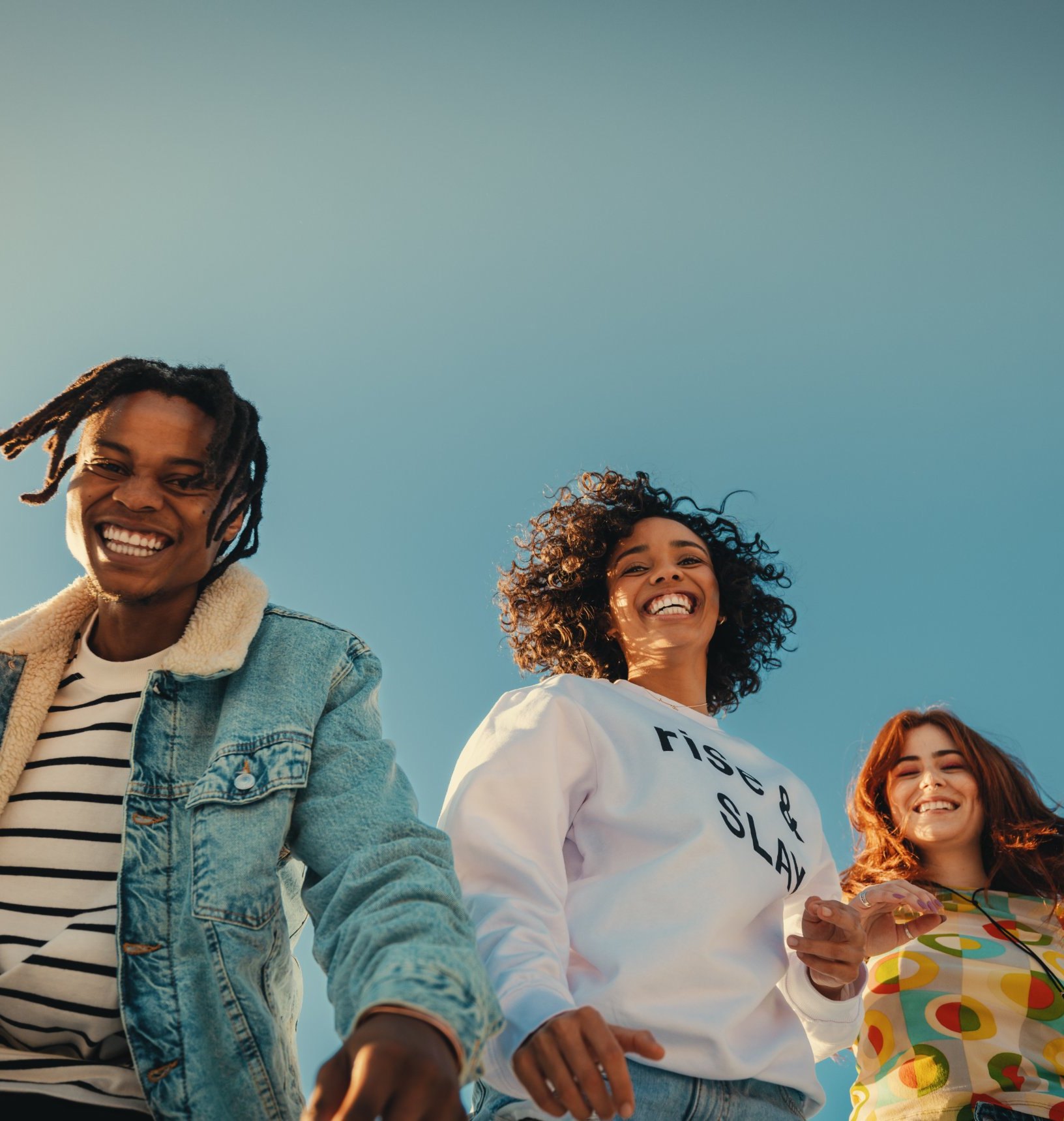 Four friends laughing under a clear blue sky